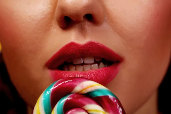 Close-up of beautiful girl\'s lower part of face. lips are sliding over big lollipop