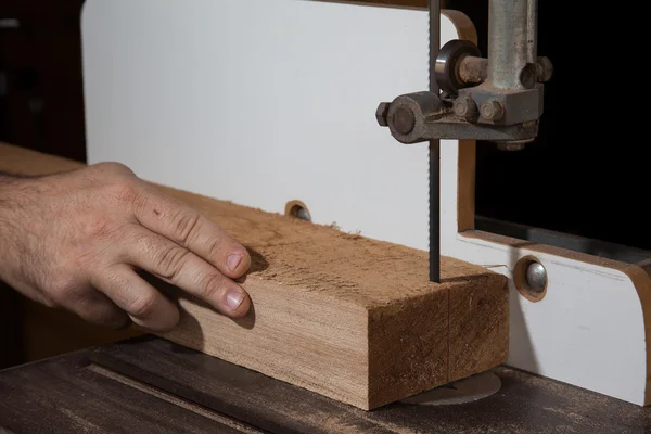 A craftsman cutting a plank of wood with bandsaw