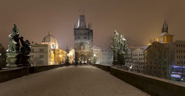 Night romantic snowy Prague Old Town with Bridge Tower and St. Francis of Assisi Cathedral from Charles Bridge with its baroque Statues, Czech republic