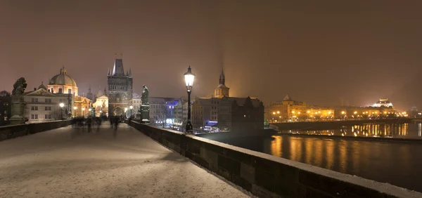 Night romantic snowy Prague Old Town with Bridge Tower and St. Francis of Assisi Cathedral from Charles Bridge with its baroque Statues, Czech republic