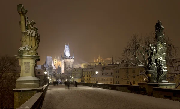 Night romantic snowy Prague Lesser Town with Bridge Tower and St. Nicholas\' Cathedral from Charles Bridge, Czech republic