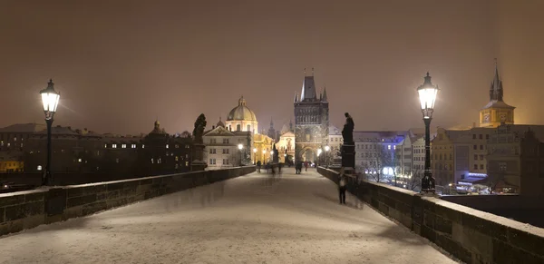 Night romantic snowy Prague Old Town with Bridge Tower and St. Francis of Assisi Cathedral from Charles Bridge with its baroque Statues, Czech republic