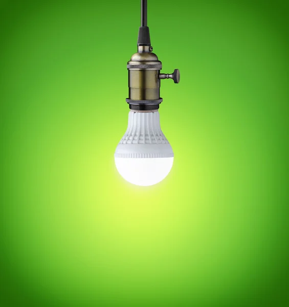 Glowing LED bulb on green background