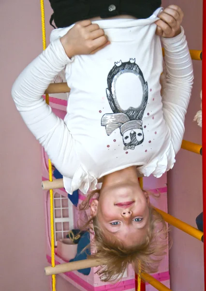 Child hanging upside down on the rings