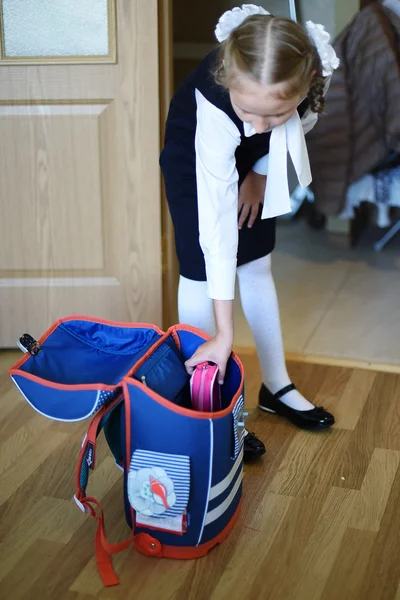 Schoolgirl home puts a briefcase and going to school.