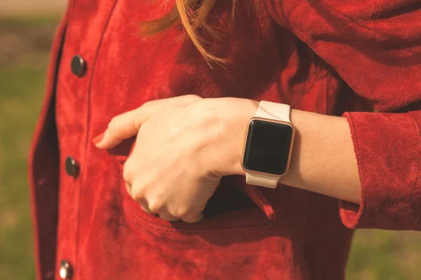 Female hand with smart watches in pocket of red jacket