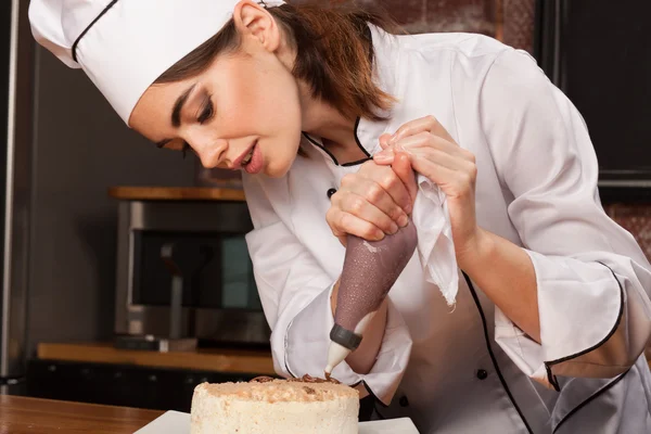 Female chef cook preparing a sweet cake in the kitchen