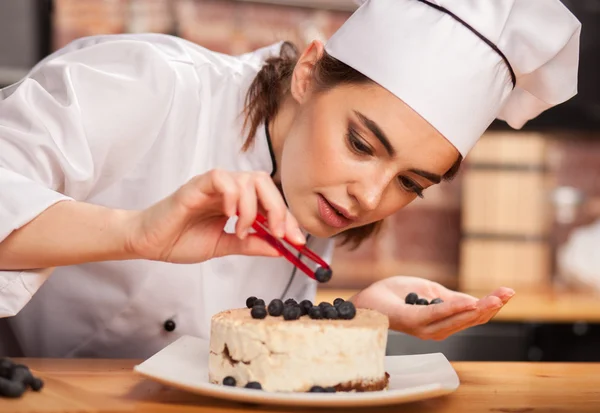 Female chef cook preparing a sweet cake in the kitchen.