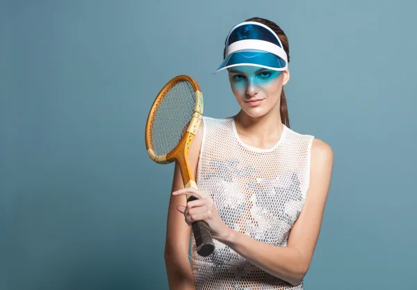 Young woman tennis player in sun visor holding tennis racquet