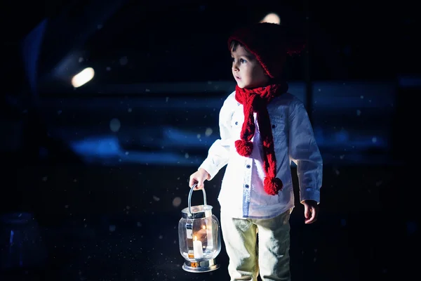Sweet boy, holding a lantern, looking at a light coming through