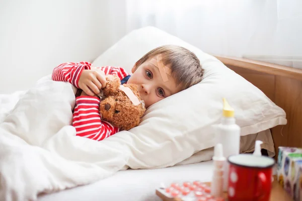 Sick child boy lying in bed with a fever, resting