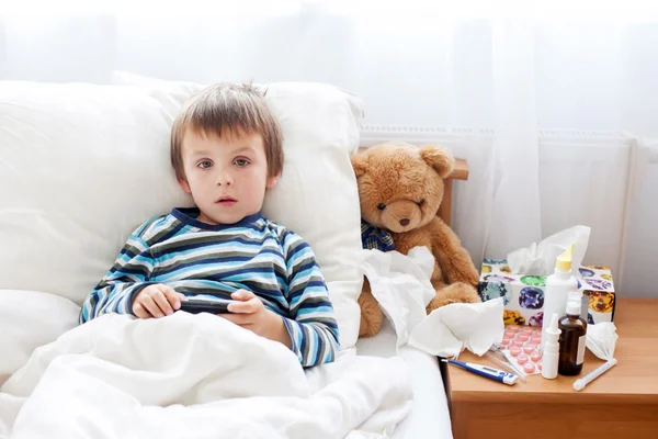 Sick child boy lying in bed with a fever, resting