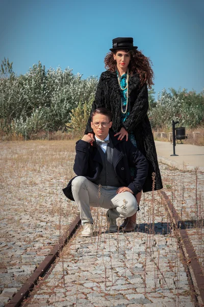 Retro fashionable woman and man standing on railroad in vintage