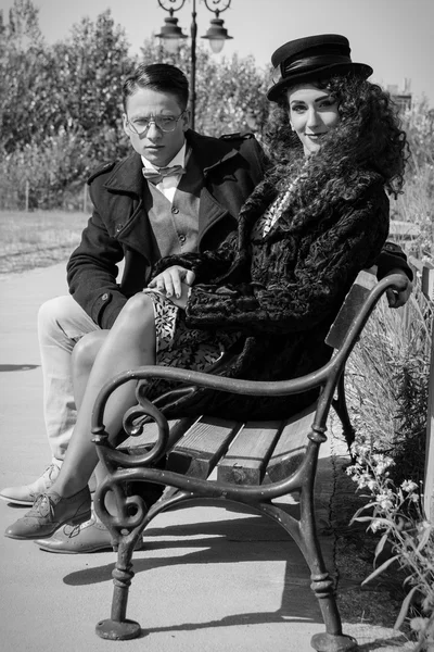 Young fashion elegant stylish retro couple sitting on bench