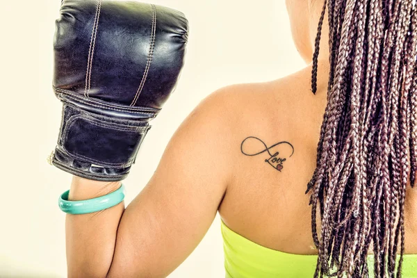 Photo of woman from behind showing black boxing glove with love