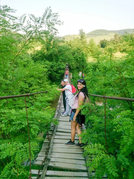 Canopy bridge and group of people  wearing backpacks on footbridge crossing it