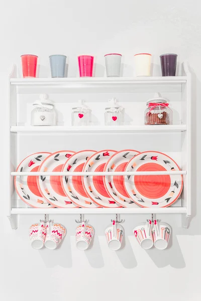 Closeup of Colourful Plates and Dinnerware in a Cupboard on Whit