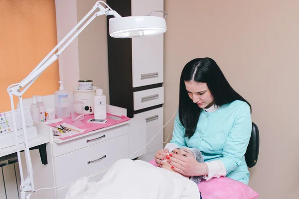 Dneprodzerzhinsk, Ukraine - March 28, 2016: Young beautiful cosmetologist makes anti-aging treatments elderly woman in cosmetology cabinet