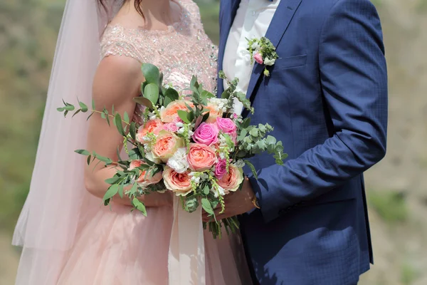 Bride holding a beautiful bridal bouquet. Wedding bouquet of peach roses by David Austin,  single-head pink rose aqua, eucalyptus, ruscus, gypsophila