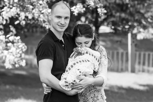 Happy couple holding their newborn daughter in her arms. Outdoors.Black and white photography