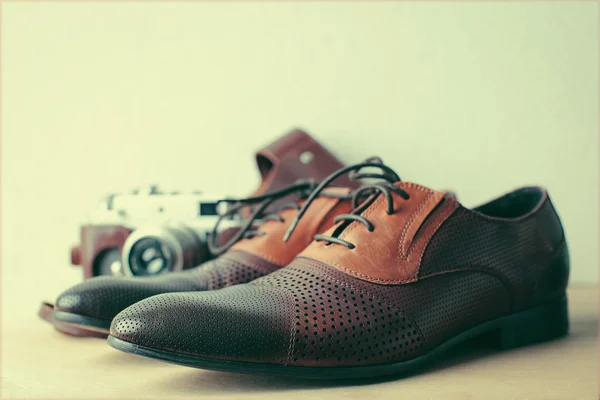 Leather man\'s shoes and a camera