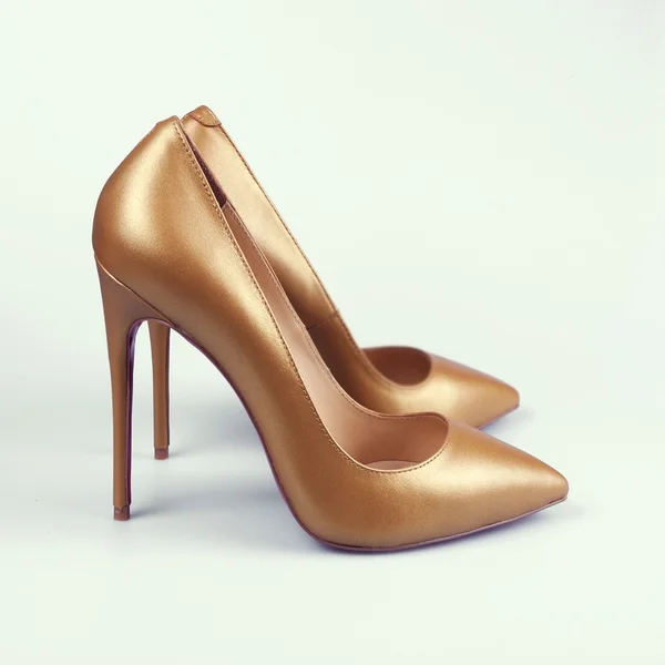 Close-up of female high-heeled shoes over white background