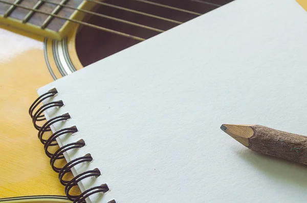 Notebook and wooden pencil on guitar