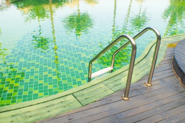 Green swimming pool with teak wood flooring