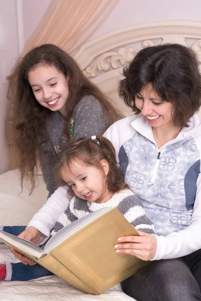 Mom reading a book with children.