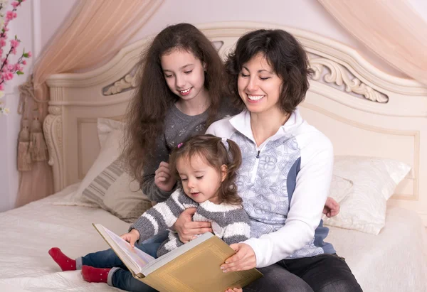 Mom reading a book with children.