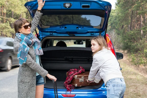 Mother and daughter traveling by car with suitcases.