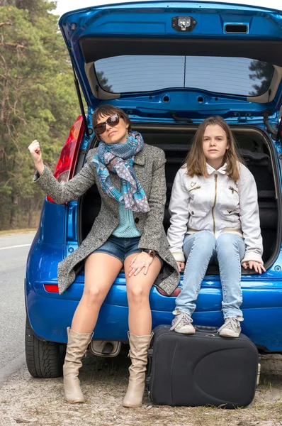 Mother and daughter traveling and waiting for help at the road
