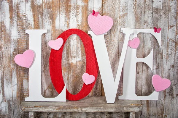 Love word with hearts on wooden planks background