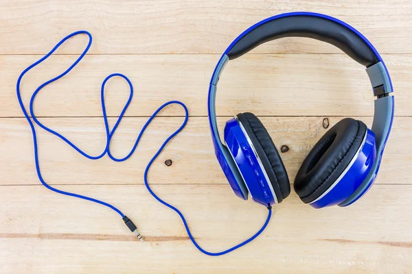 Blue headphones on wood desk.