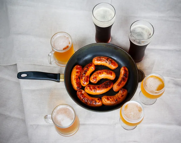 Grilled sausages and beer glasses on table. Top view