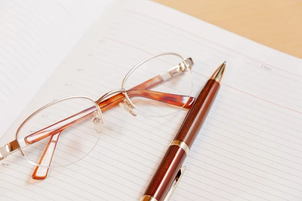 Daily planner with glasses and pen on the table. Selective focus