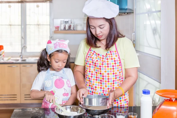 Asian mother and daughter enjoy making pancake in kitchen at homej