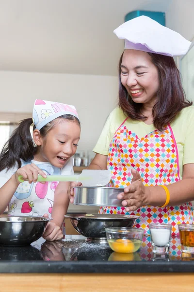 Asian mother and daughter enjoy making pancake in kitchen at homej