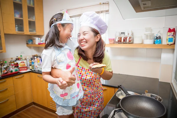 Asian mother and daughter enjoy making pancake in kitchen at home