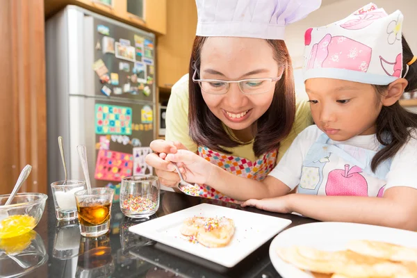 Little Asian girl and mom enjoy decorate pancake with decorate sugar pill