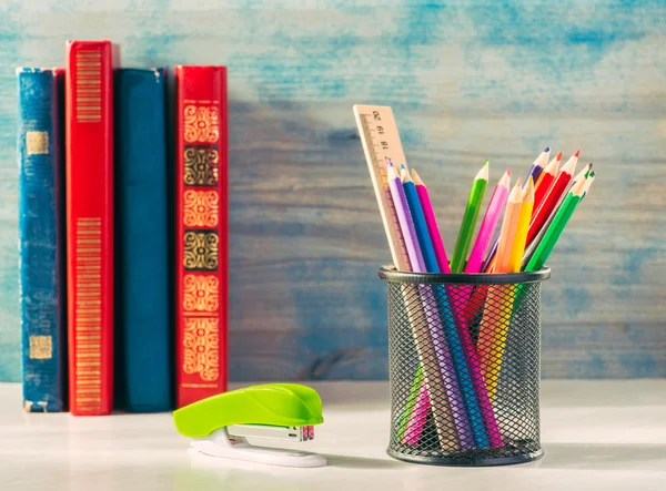 Books and pencils on wooden shelf