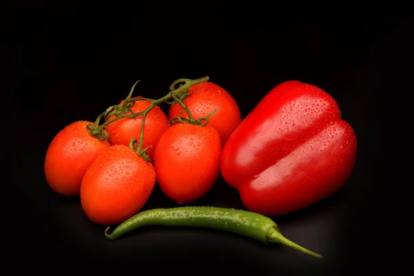 Tomatoes, sweet and chilli pepper on black background