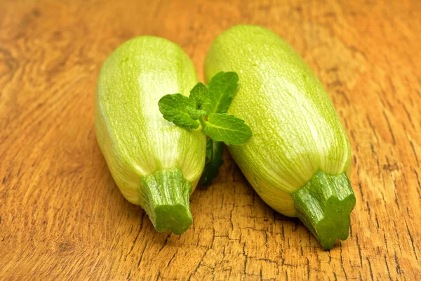 Pair of fresh green zucchini onold wooden background