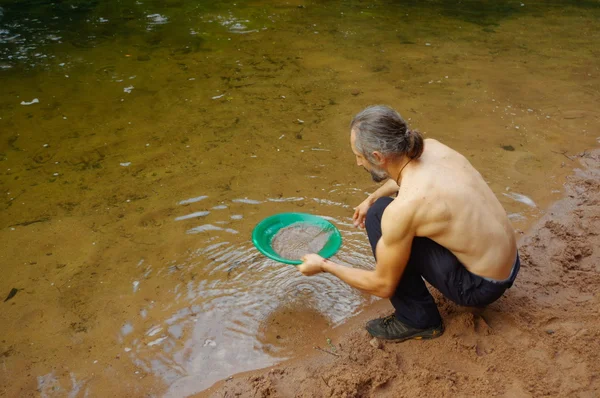 Man prospector gold panning in a river with  sluice box