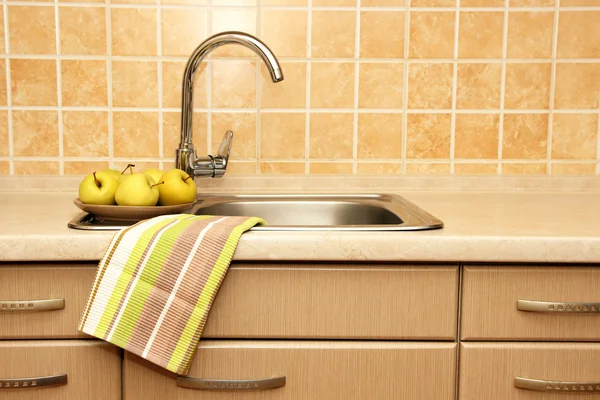 A plate of apples, standing at the kitchen sink and towel.