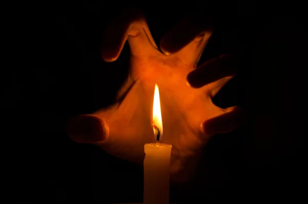 Spell and Spirituality Topic: Witches hand holding a candle on a dark background