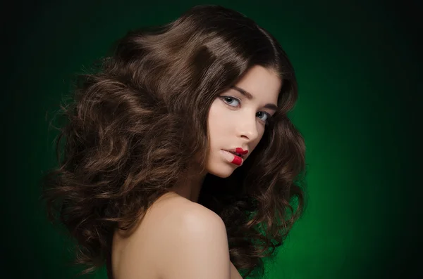 Hair and make-up topic: a very beautiful girl model with lush hair and creative make-up on green background