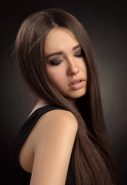 Dramatic portrait of a girl theme: portrait of a young beautiful girl on a dark background in the studio