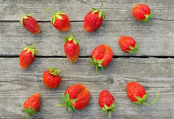 Summer berries topic: Ripe red strawberries bunch of lies on gray wooden table in the garden, view from above