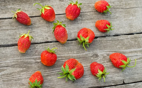 Summer berries topic: Ripe red strawberries bunch of lies on gray wooden table in the garden, view from above